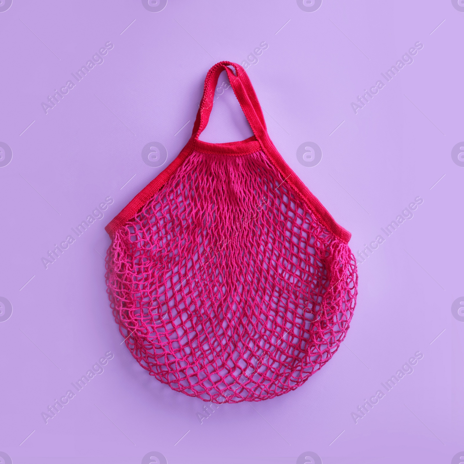 Photo of Empty net bag on lilac background, top view