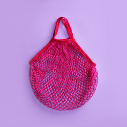 Empty net bag on lilac background, top view