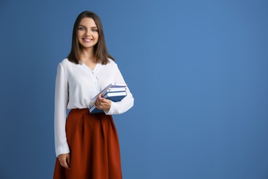 Photo of Portrait of female teacher with notebooks on color background