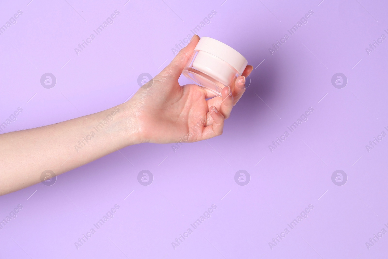 Photo of Woman holding jar of cream on violet background, closeup. Space for text