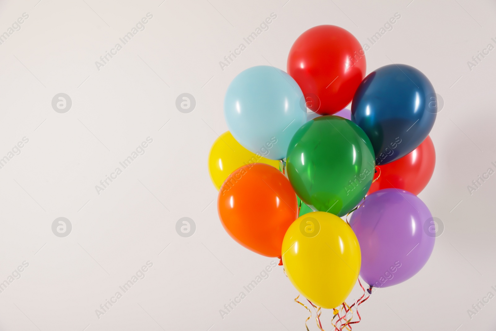 Photo of Bunch of bright balloons on light background, space for text. Celebration time