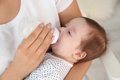 Photo of Woman feeding her baby from bottle at home, closeup