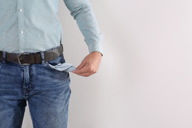 Man showing empty pocket on light background, closeup. Space for text