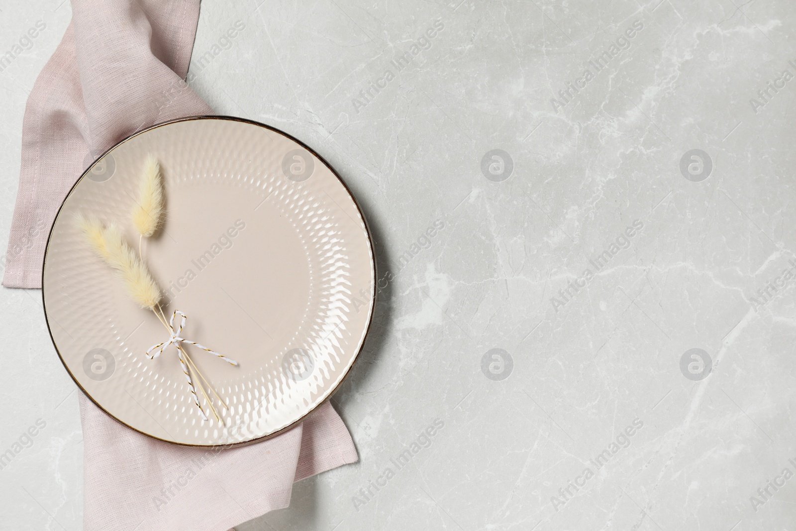 Photo of Elegant plate with spikes and napkin on marble table, top view. Space for text