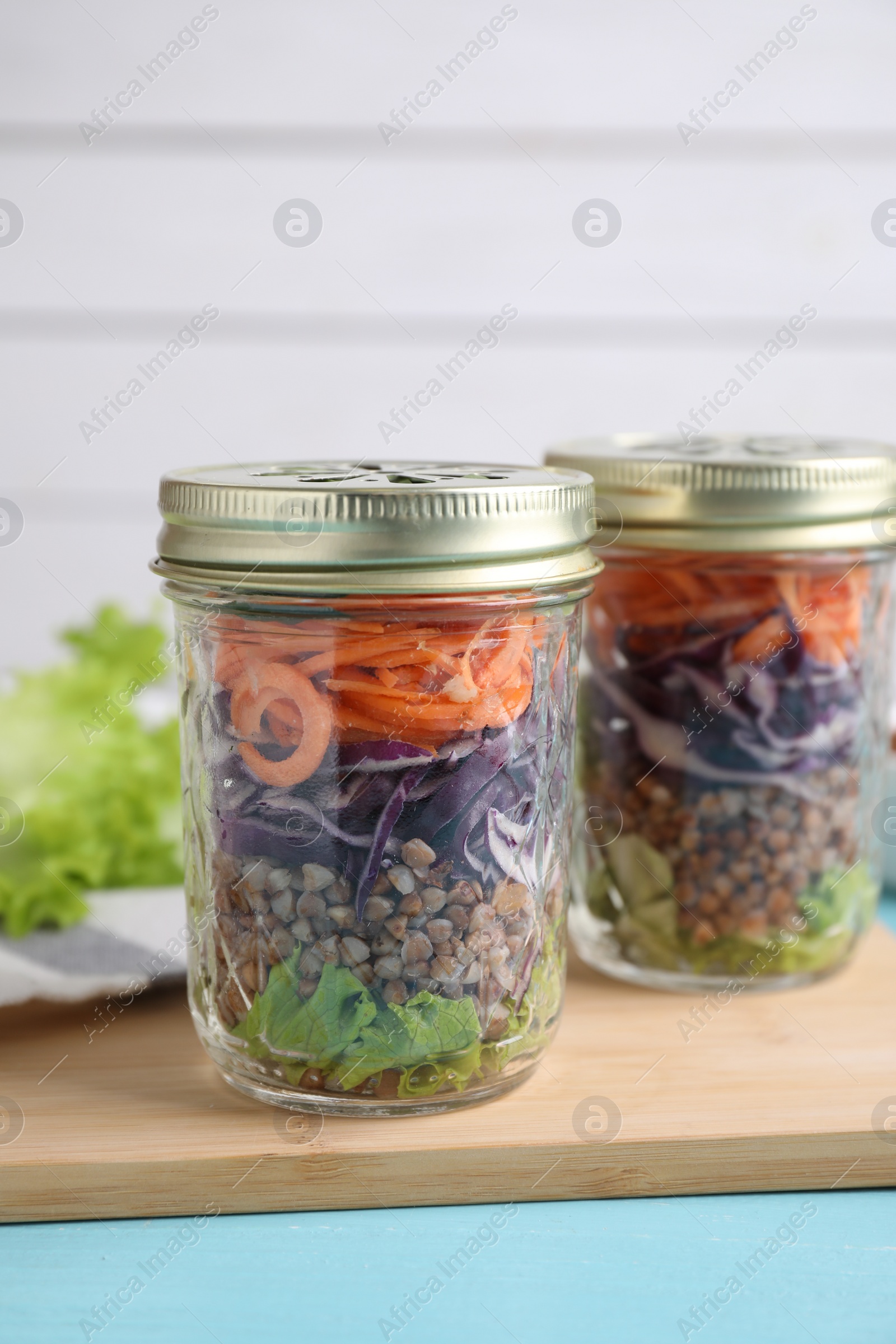 Photo of Glass jars with healthy meal on light blue wooden table