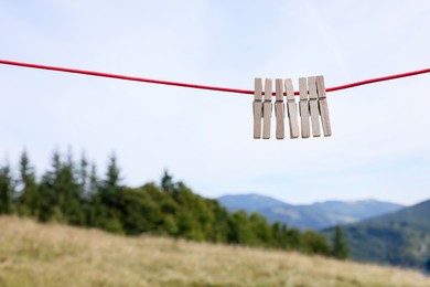 Photo of Wooden clothespins hanging on washing line in mountains