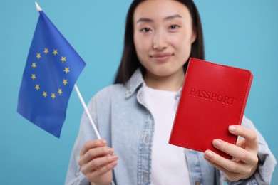 Photo of Immigration to European Union. Woman with passport and flag on light blue background, selective focus
