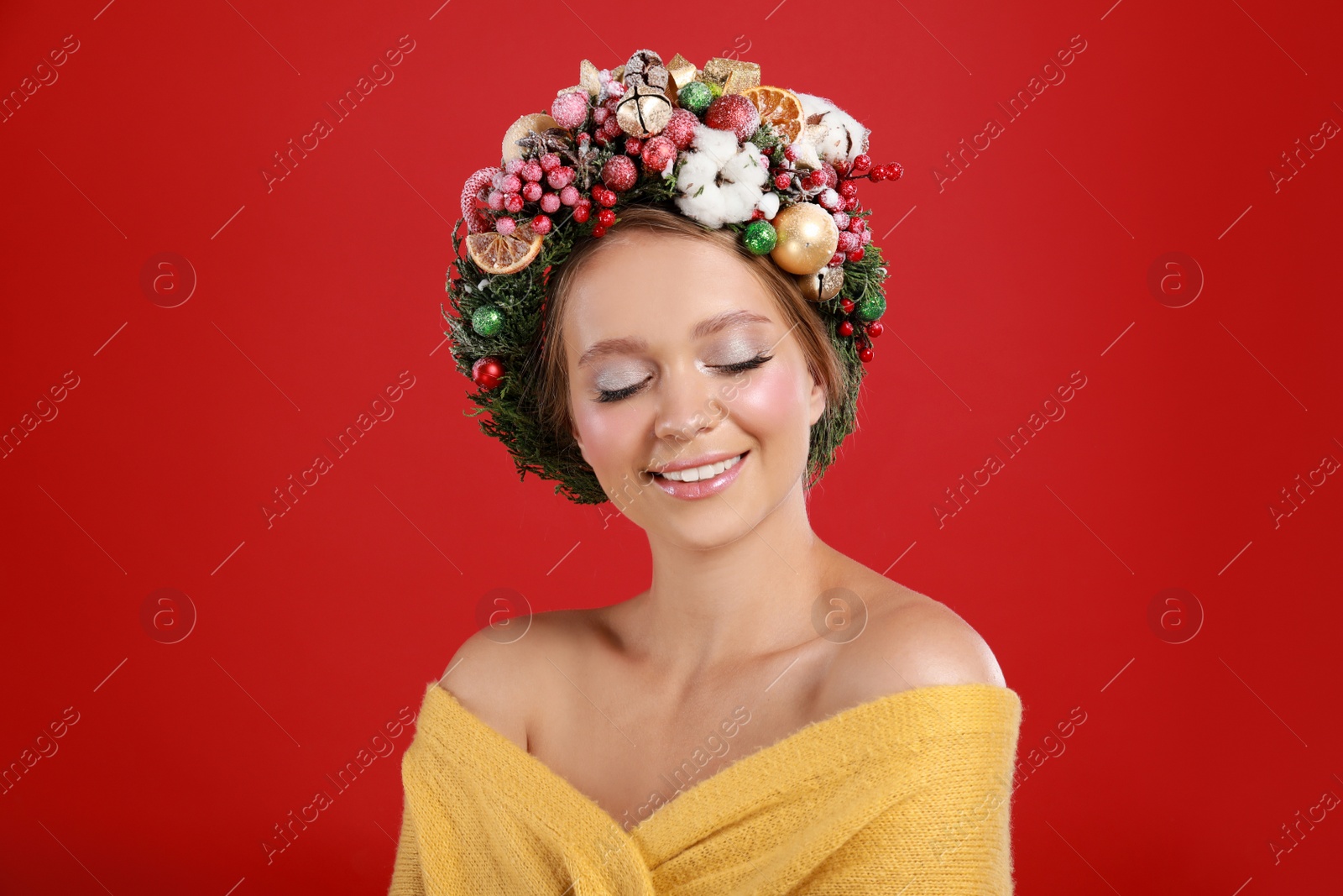 Photo of Beautiful young woman wearing Christmas wreath on red background