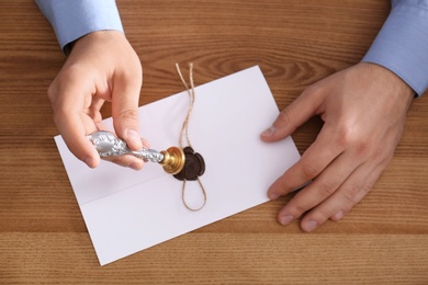 Male notary sealing document at wooden table, top view