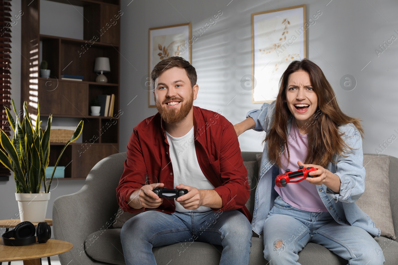 Photo of Couple playing video game with controllers at home