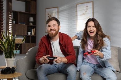 Couple playing video game with controllers at home