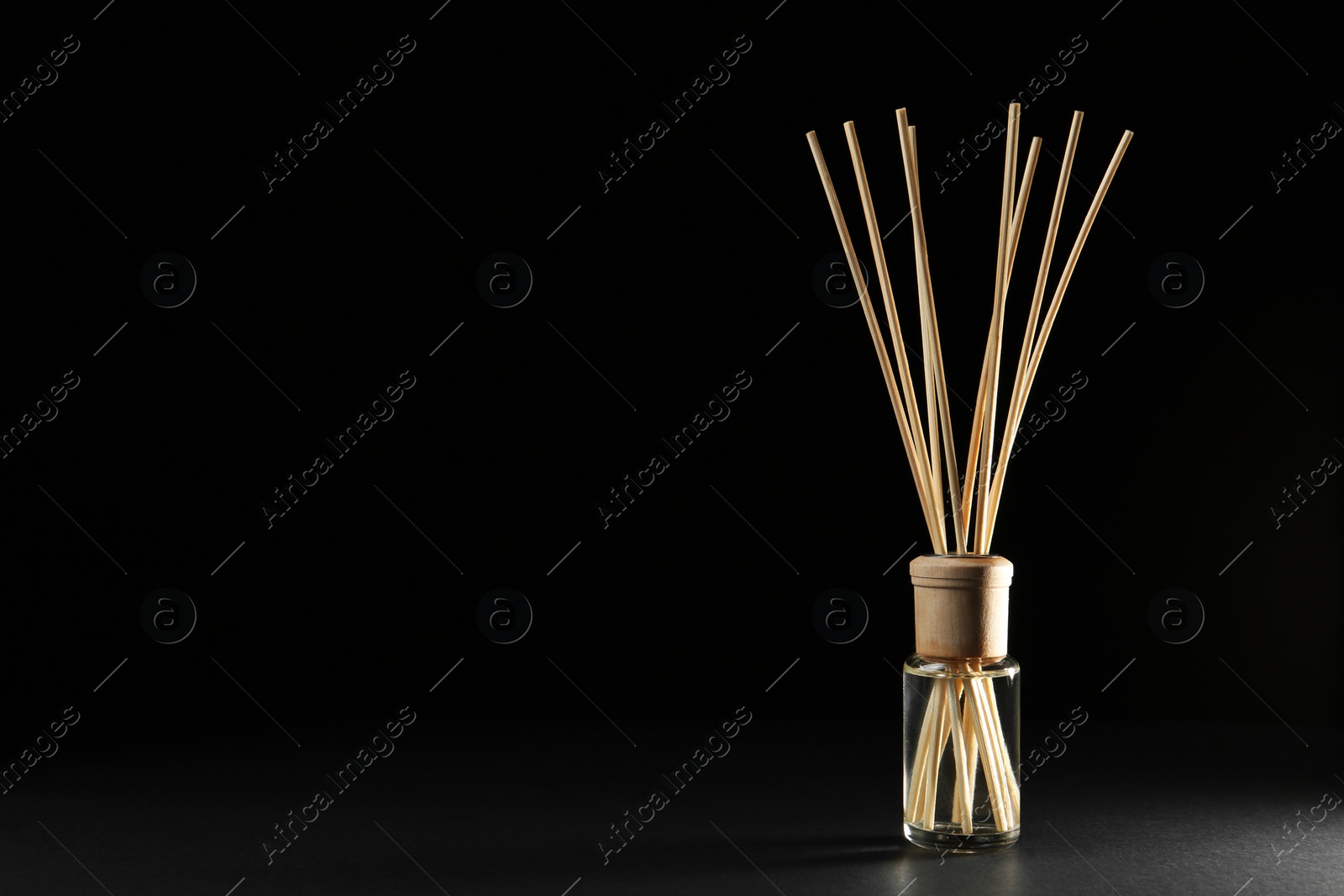 Photo of Reed air freshener on black background, space for text