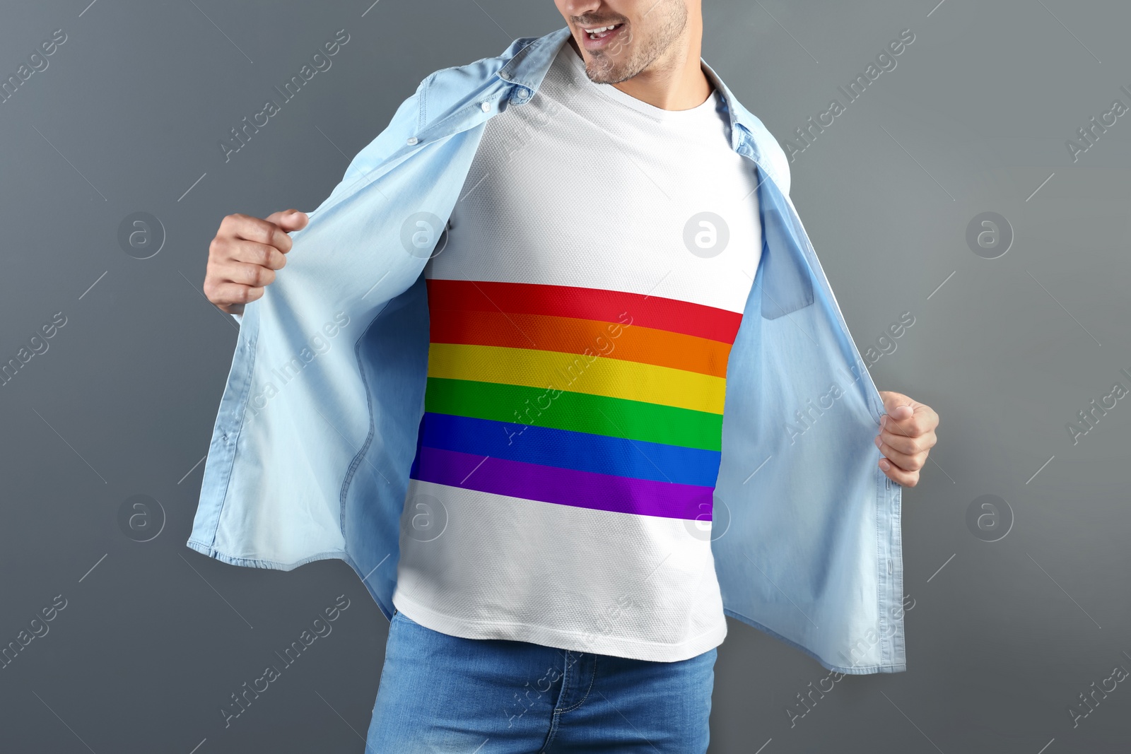 Image of Young man wearing white t-shirt with image of LGBT pride flag on grey background