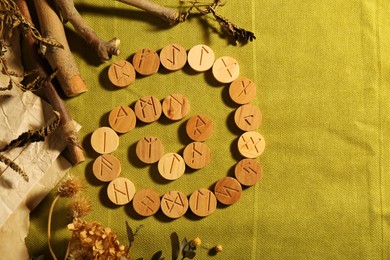 Many wooden runes and dried plants on olive fabric, flat lay. Space for text