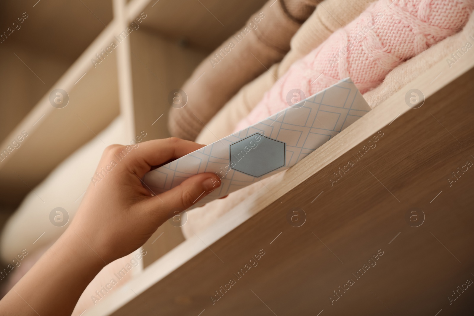 Photo of Woman putting scented sachet in wardrobe, closeup