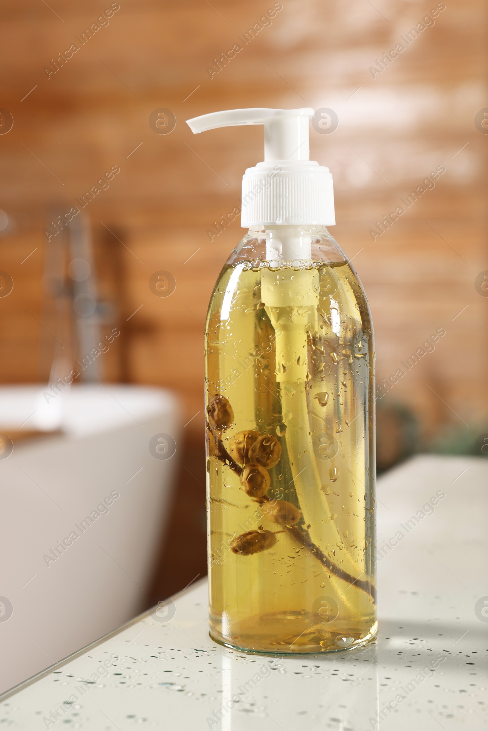 Photo of Dispenser of liquid soap on white table in bathroom