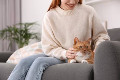 Happy woman with her cute cat on sofa at home, closeup