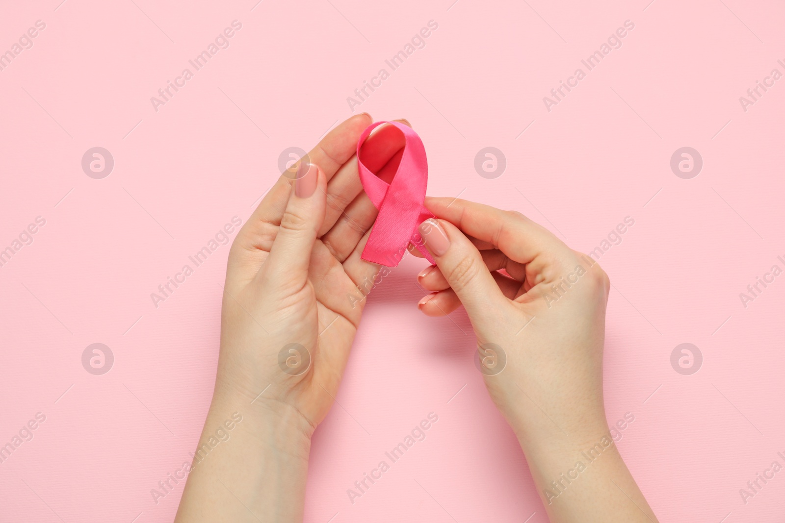 Photo of Woman with pink ribbon on color background, top view. Breast cancer awareness