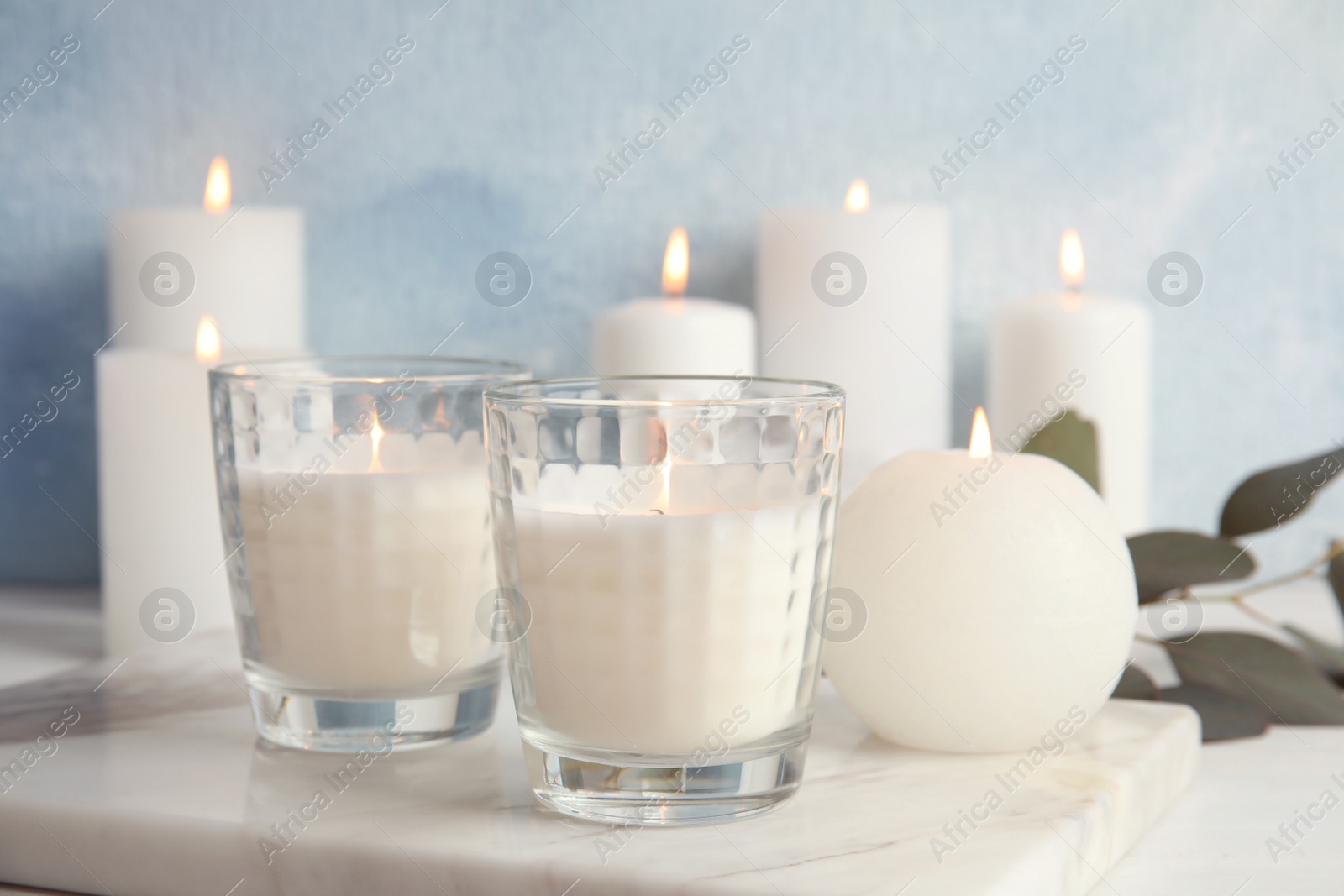 Photo of Burning candles on table against color background. Space for text