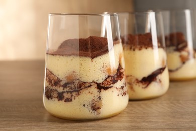 Delicious tiramisu in glasses on wooden table, closeup