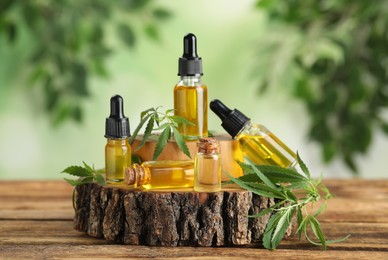 Hemp oil and leaves on wooden table against blurred background