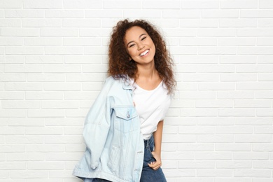 Young African-American woman with beautiful face near white brick wall