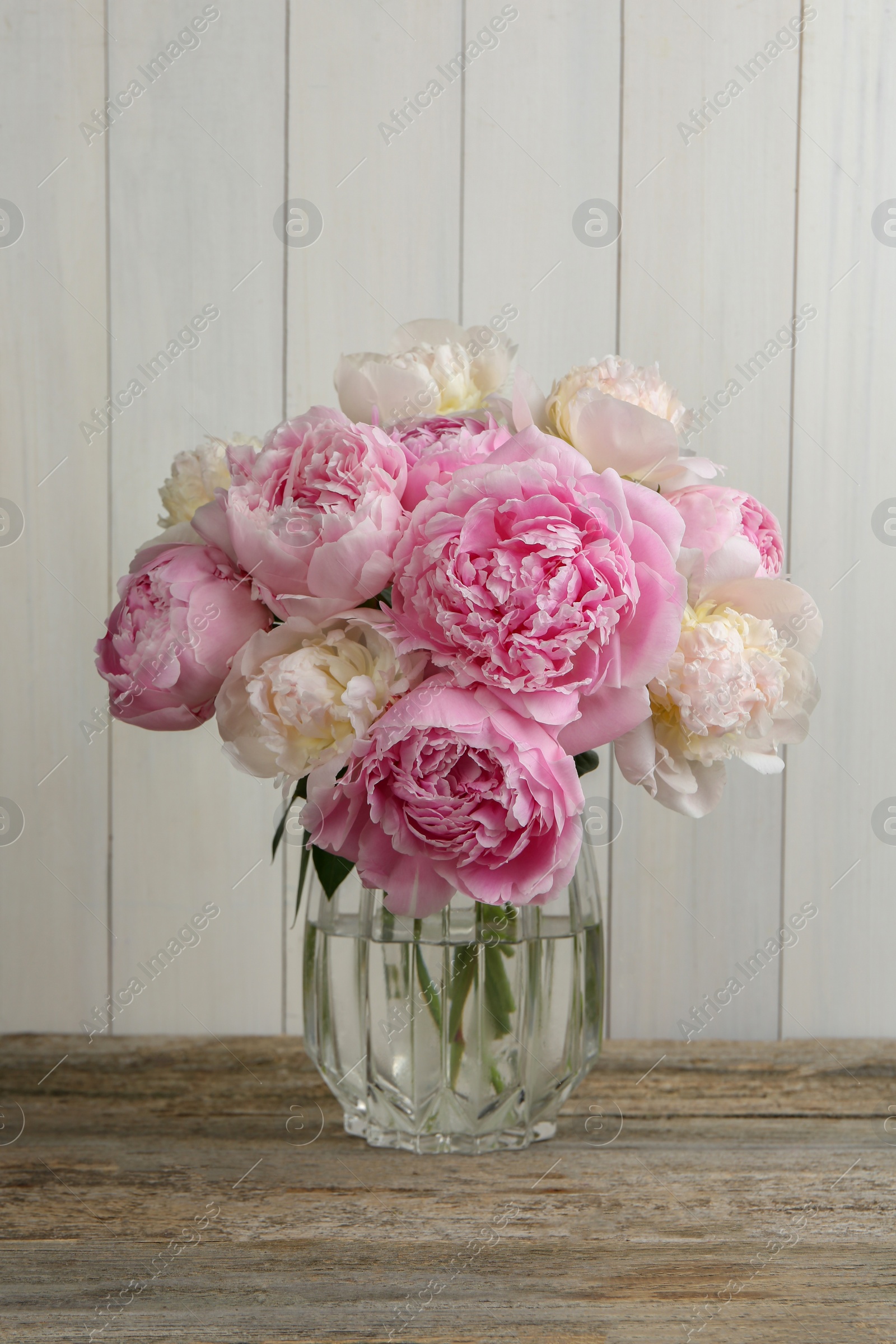 Photo of Beautiful peonies in vase on wooden table