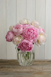 Beautiful peonies in vase on wooden table