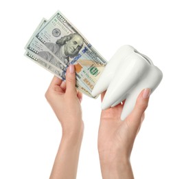 Photo of Woman holding ceramic model of tooth and dollar banknotes on white background, closeup. Expensive treatment