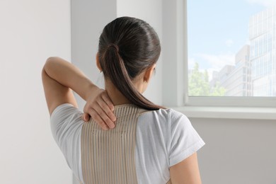 Photo of Woman with orthopedic corset in room, back view