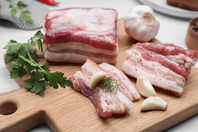 Photo of Tasty pork fatback with garlic and herbs on white table, closeup