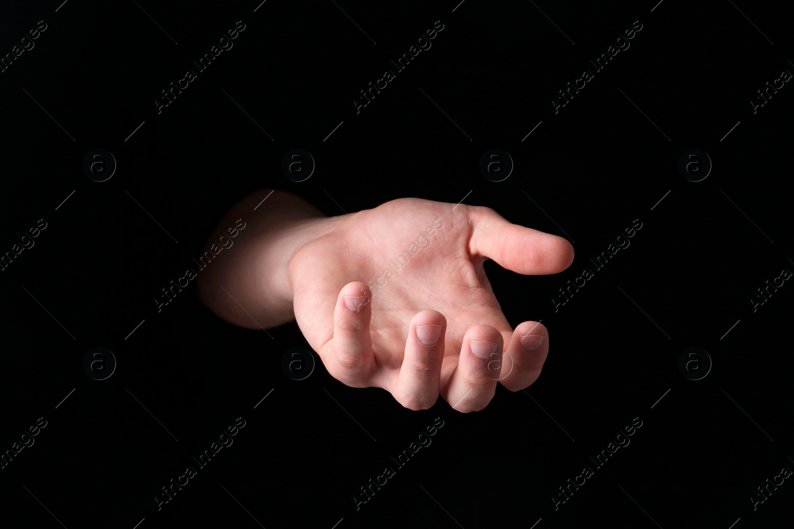 Photo of Man holding something in his hand on black background, closeup