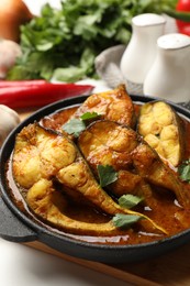 Tasty fish curry and ingredients on table, closeup. Indian cuisine