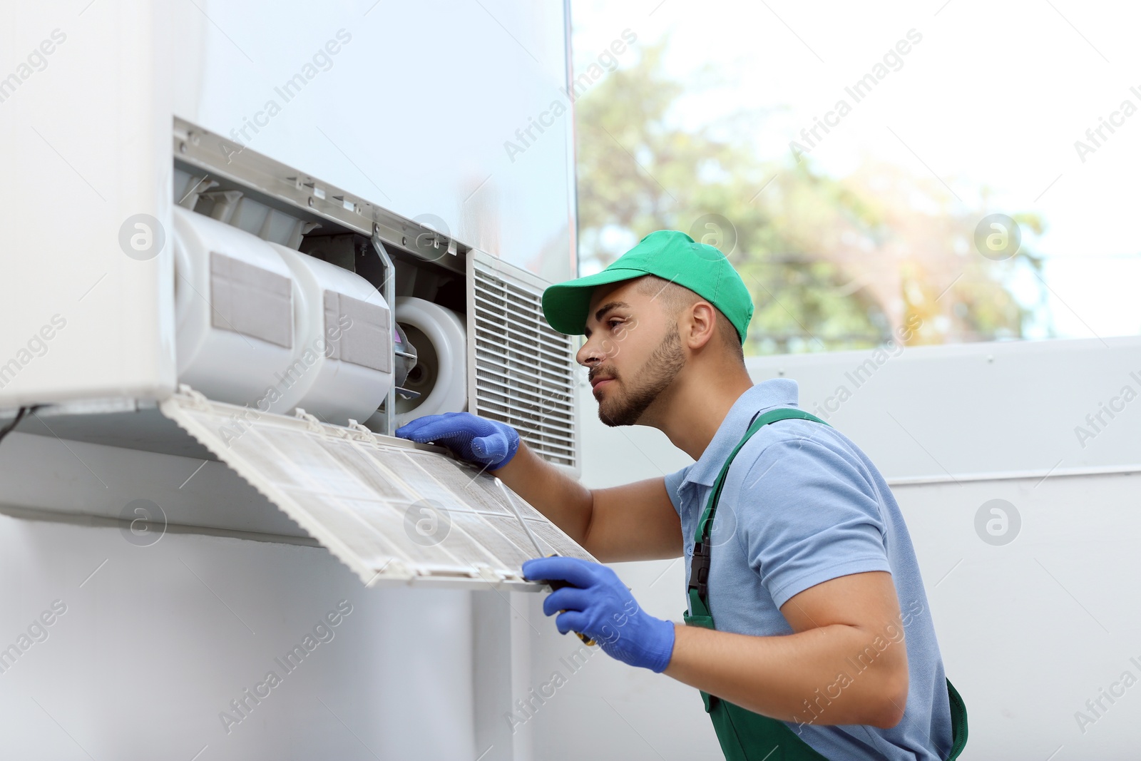 Photo of Professional technician maintaining modern air conditioner indoors