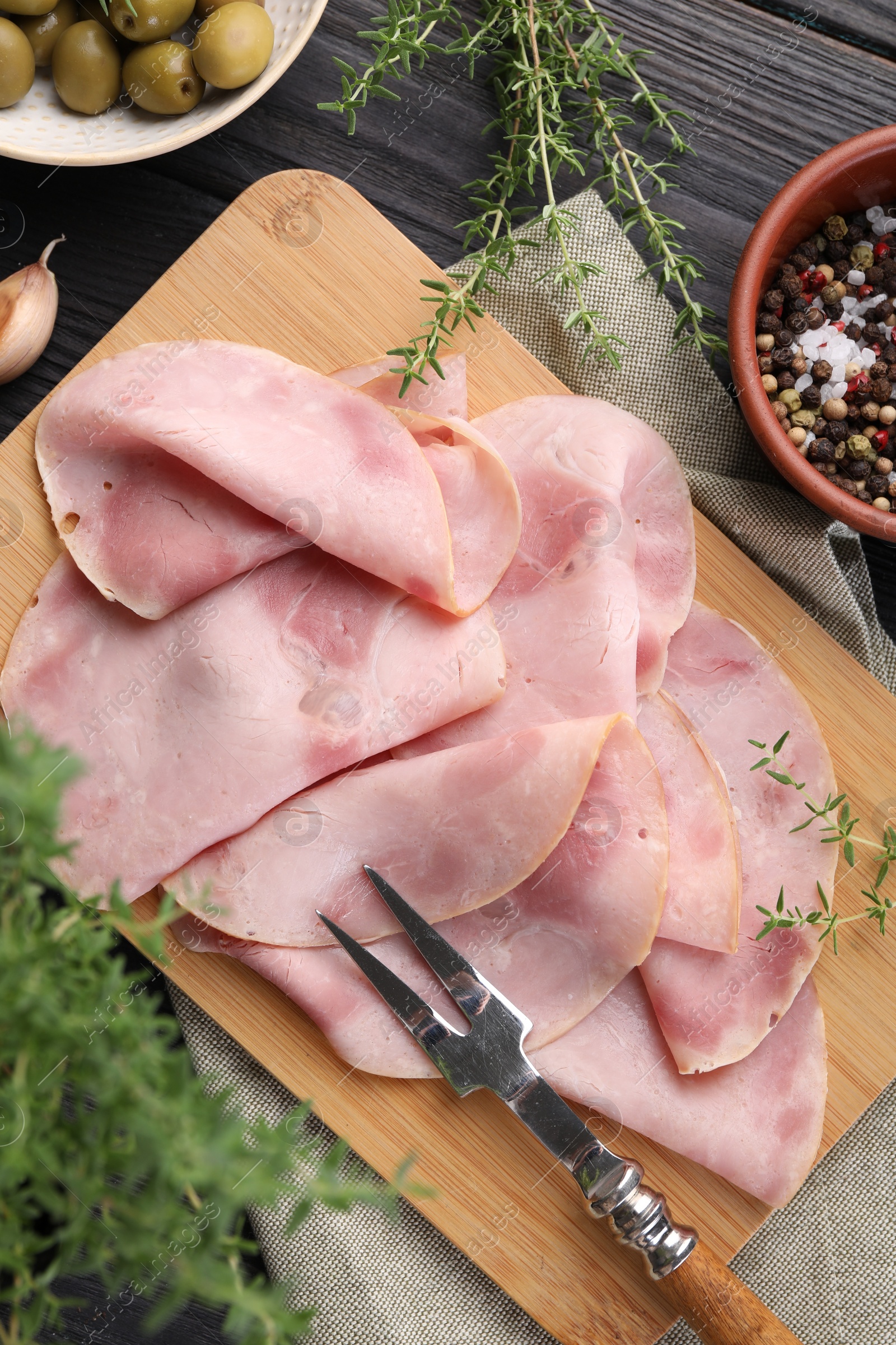 Photo of Slices of delicious ham served with different ingredients on dark wooden table, flat lay