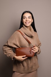 Fashionable young woman with stylish bag on beige background