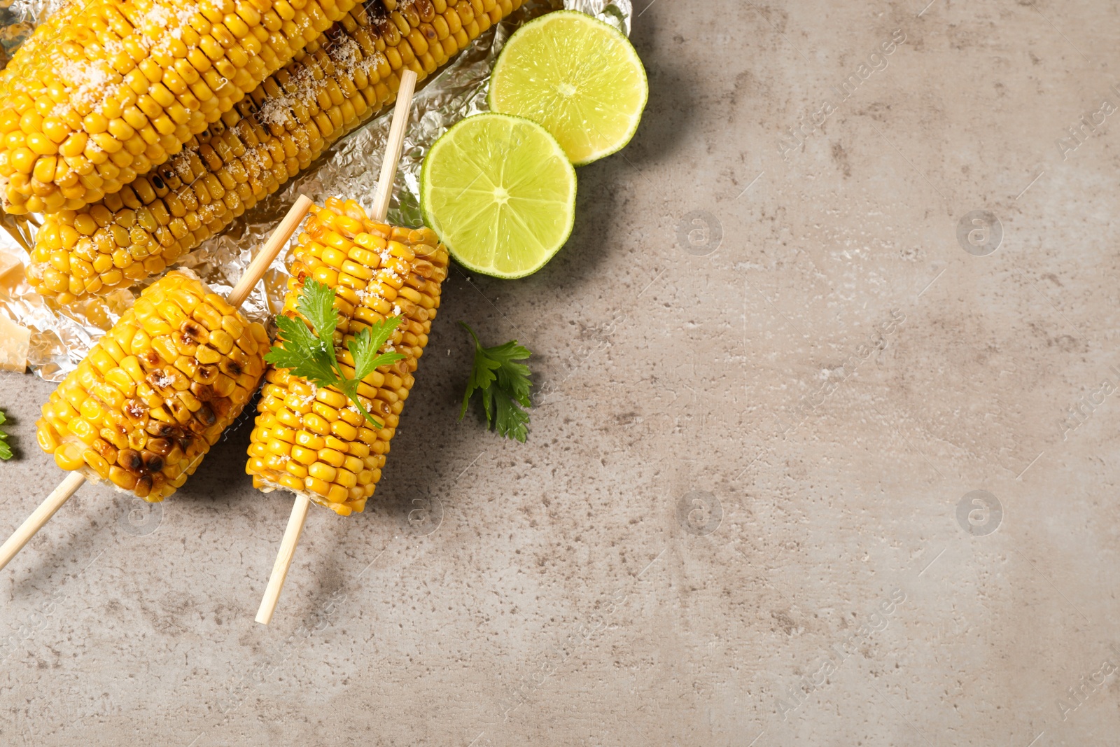 Photo of Delicious grilled corn cobs on grey table, flat lay. Space for text