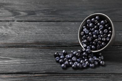 Photo of Ripe bilberries on dark wooden table. Space for text