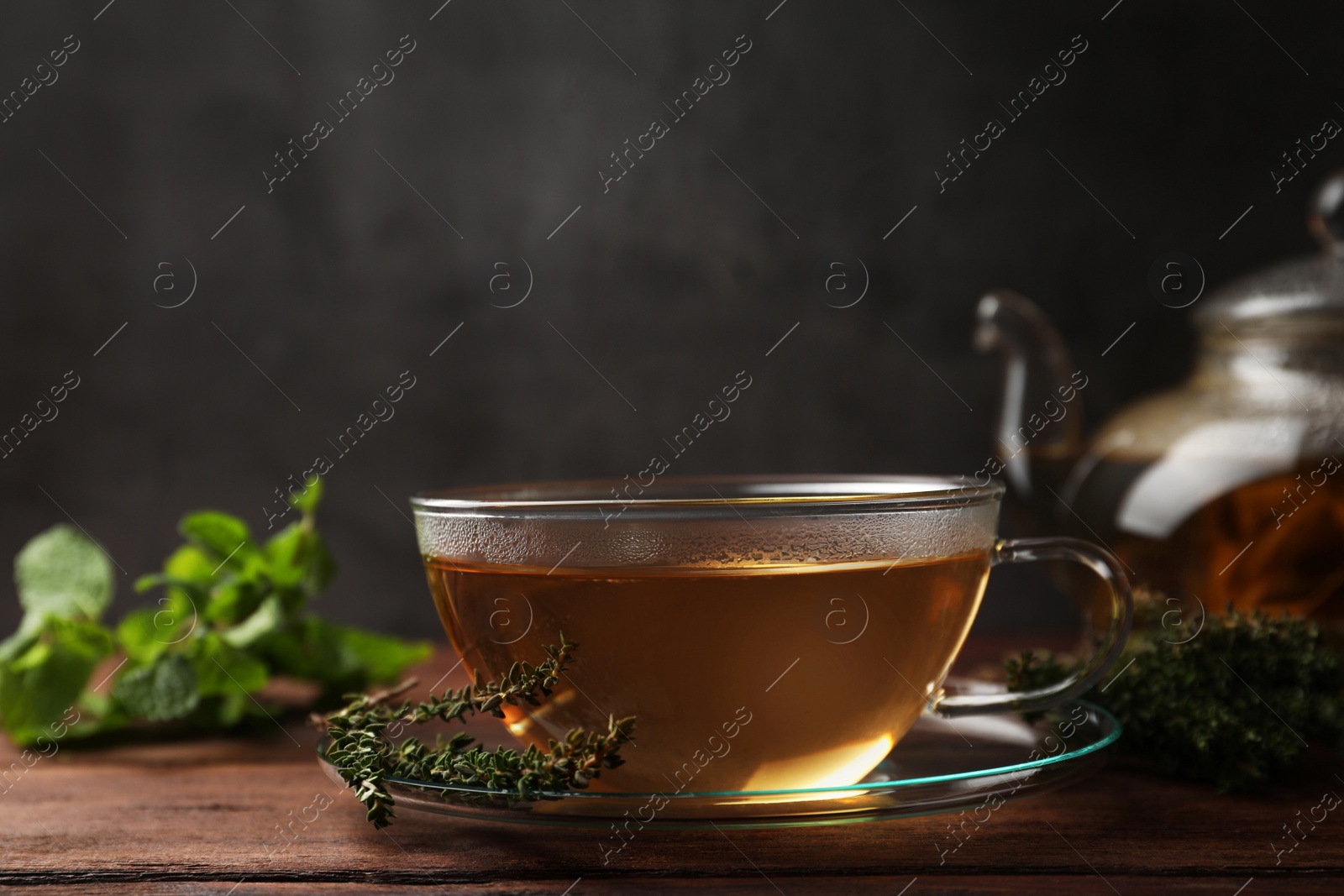 Photo of Cup of aromatic herbal tea and fresh thyme on wooden table