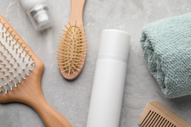 Photo of Dry shampoo sprays, towel and hairbrushes on light grey table, flat lay