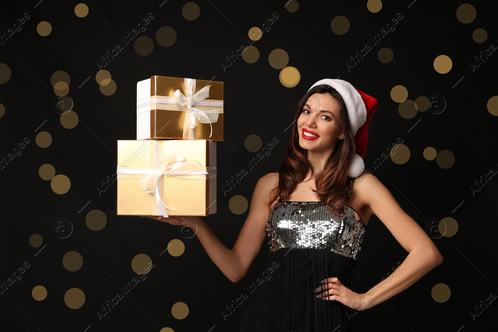 Photo of Beautiful woman wearing Santa hat with Christmas gifts on black background
