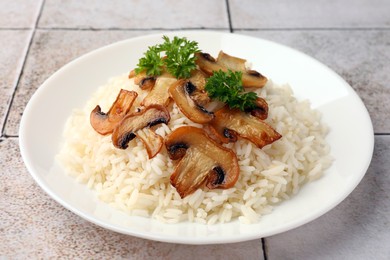 Photo of Delicious rice with parsley and mushrooms on tiled table, closeup