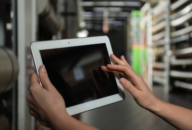 Photo of Woman with tablet in wholesale warehouse, closeup. Space for design
