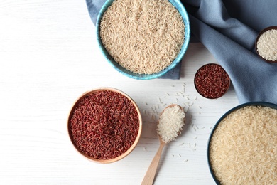 Photo of Flat lay composition with brown and other types of rice on wooden background