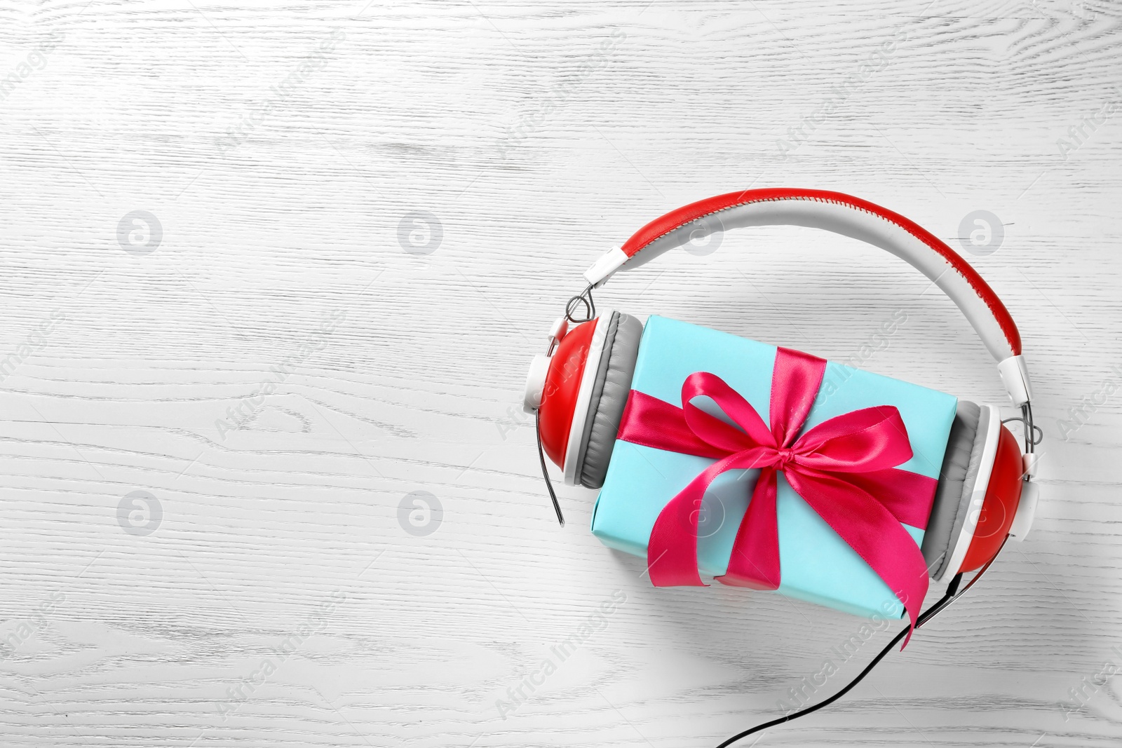 Photo of Flat lay composition with gift box and headphones on wooden background. Christmas music concept