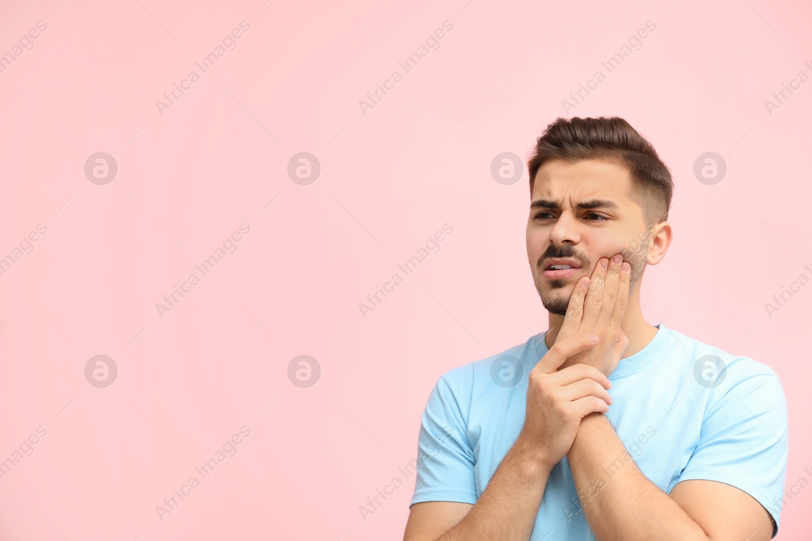 Photo of Young man suffering from strong tooth pain on color background, space for text