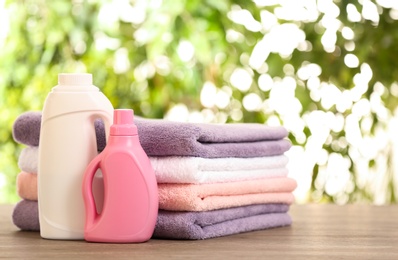 Photo of Stack of clean towels with detergents on table against blurred background. Space for text