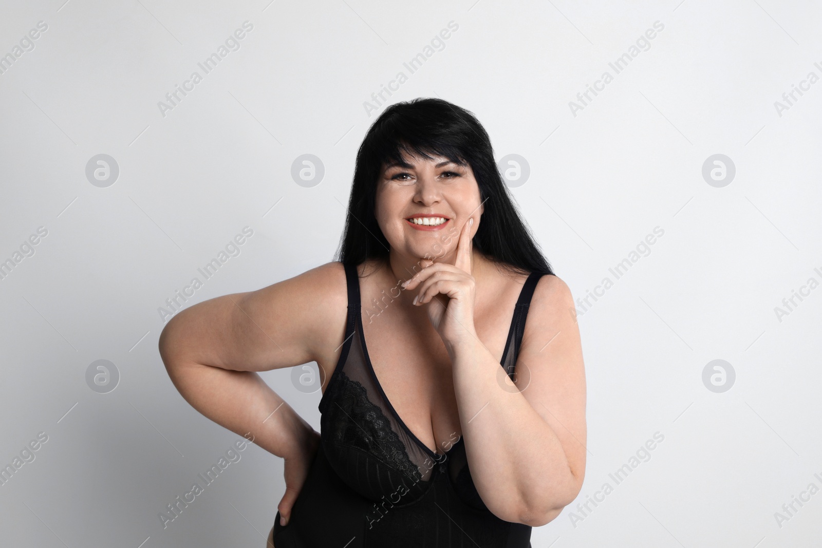 Photo of Beautiful overweight woman in black underwear on light background. Plus-size model