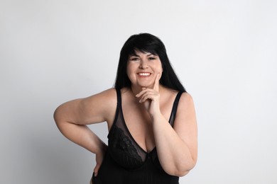 Photo of Beautiful overweight woman in black underwear on light background. Plus-size model