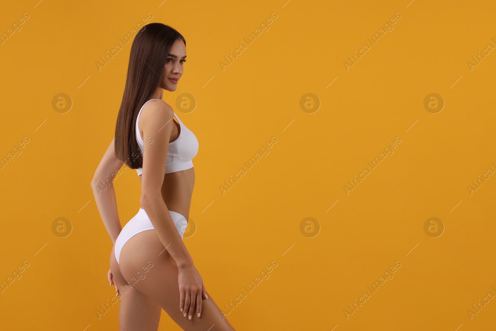 Photo of Young woman in stylish white bikini on orange background. Space for text